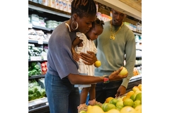 Family shopping in a supermarket, looking at fruits.